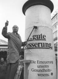 Der Bundesminister für Arbeit und Sozialordnung, Norbert Blüm, klebt ein Plakat zur Strukturreform der Krankenversicherung an eine Litfaßsäule ("Die Erneuerung unseres Gesundheitswesens"), 23. Februar 1988