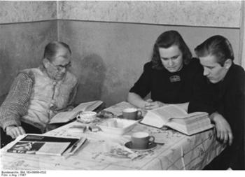 Familie sitzt am Tisch und liest, 1947