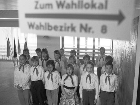 Ein Kinderchor empfängt die Bürgerinnen und Bürger in einem Wahllokal.