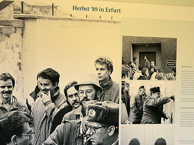 Blick auf die Ausstellungstafel „Herbst `89“. Links sind Schwarz-Weiß-Fotos von der Öffnung der Tür der Bezirksverwaltung Erfurt des MfS durch den Militärstaatsanwalt zu sehen. Rechts ist kleingedruckter Text.