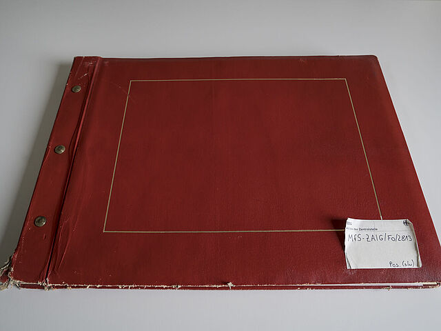 Draufsicht des roten Albums vom Mauerbau. Unten rechts klebt ein Zettel mit der Signatur.