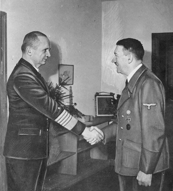 Adolf Hitler und Karl Dönitz stehen sich in einem Raum im „Führerbunker“ gegenüber und schütteln sich die Hände.