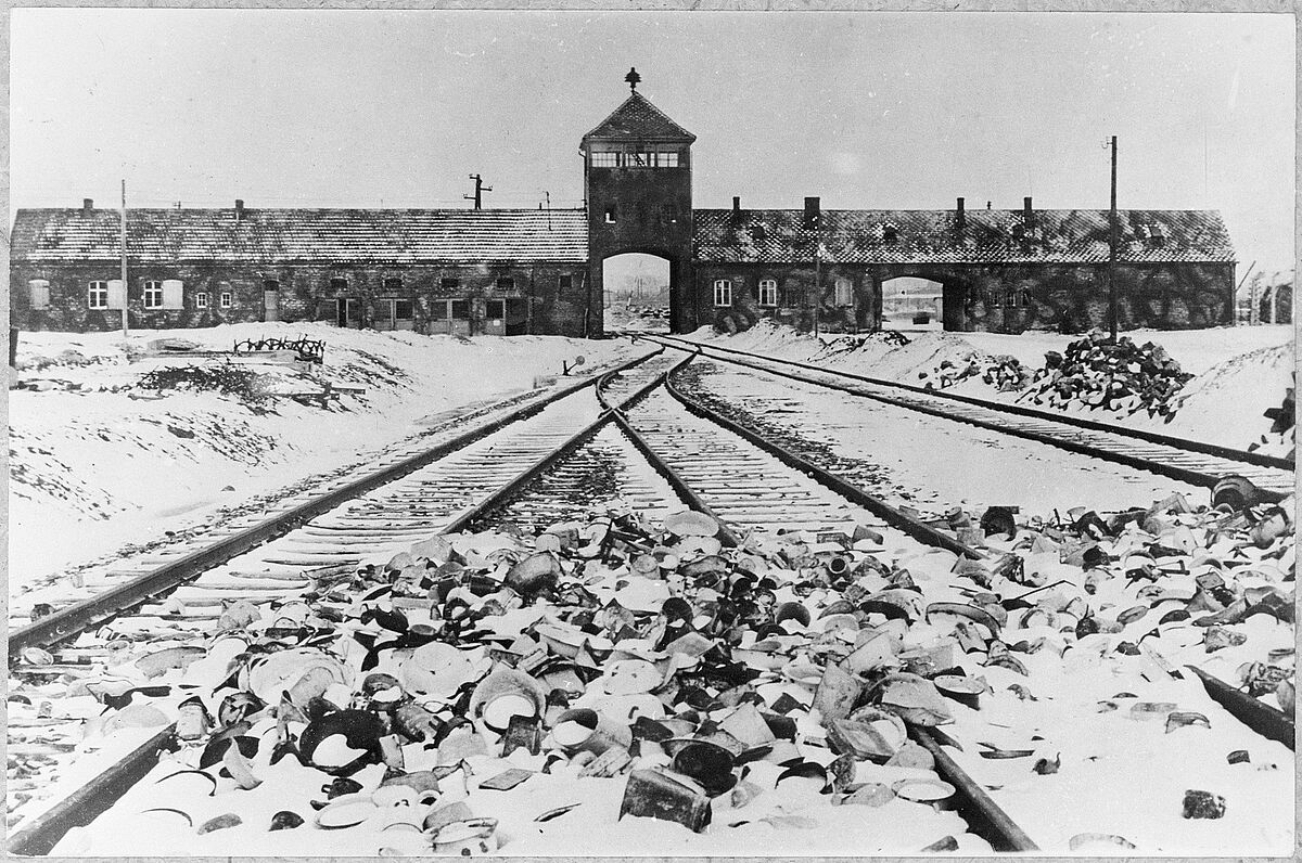 Das Vernichtungslager Auschwitz-Birkenau: Lagertor (innen) / Ausfahrt nach der Befreiung, im Vordergrund von den Wachmannschaften zurückgelassene Ausrüstungsgegenstände