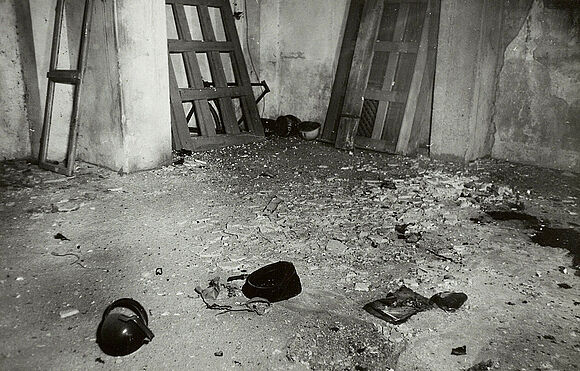 Aufgeklebte Schwarz-Weiß-Fotografie eines leeren Raumes mit Schutt und Gegenständen auf dem Boden.