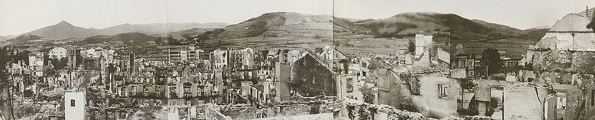 Panoramaaufnahme einer zerstörten Stadt mit Bergen im Hintergrund