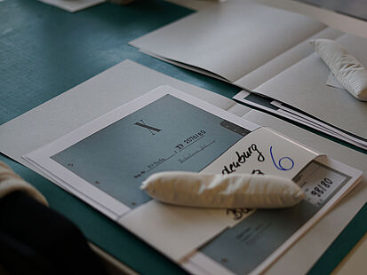 Beispielakten Kleine Säckchen aus Stoff beschweren zwei Stapel loser Blätter, die später zu einer Beispielakte zusammengefügt werden.