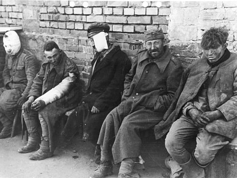 Zum Teil verwundete polnische Kriegsgefangene, die auf einer Bank sitzen.