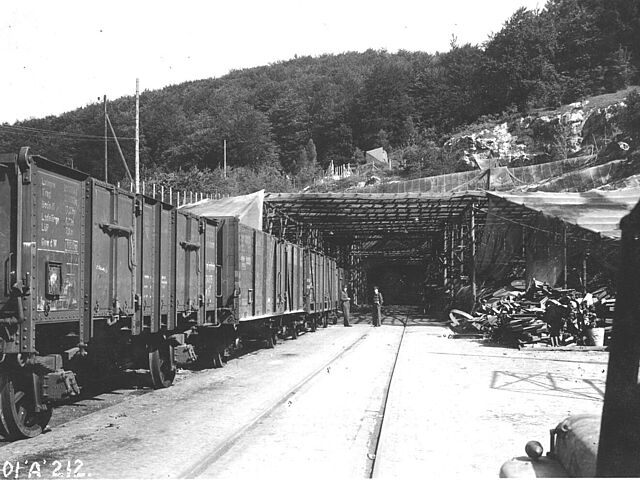 Zwei Offiziere der britischen Armee neben einem Güterzug vor dem getarnten Eingang des Fahrstollens A im KZ Mittelbau-Dora 