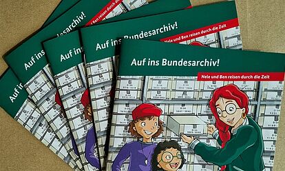 Nahaufnahmen von mehreren Ausgaben des Kinderhefts „Auf ins Bundesarchiv! – Nele und Ben reisen durch die Zeit“
