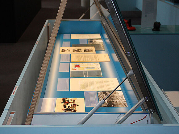 Vitrine mit offenem Deckel und Dokumenten