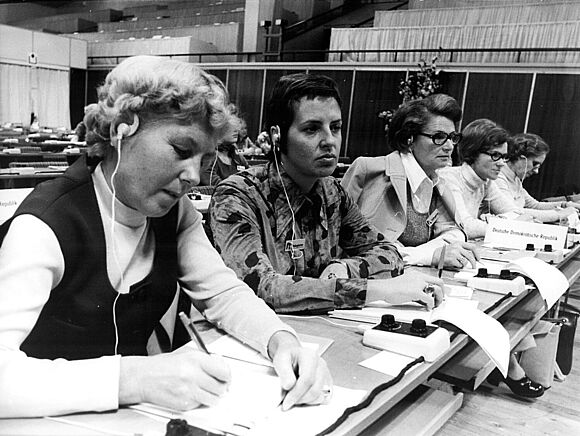 Fünf Frauen sitzen an einem Tisch und machen Notizen.