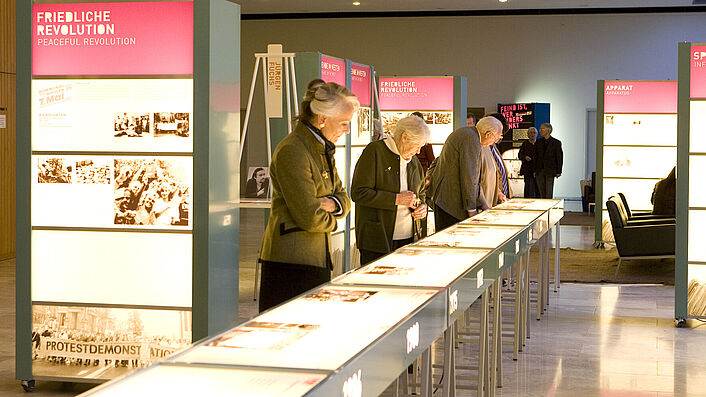 Das Bild zeigt mehrere Menschen, die sich die Wanderausstellung 'Feind ist, wer anders denkt' anschauen.
