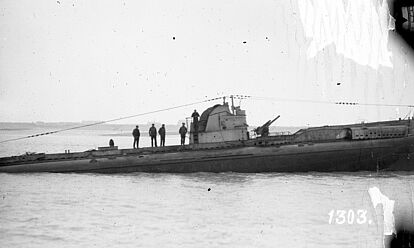 Aufgetauchtes U-Boot mit Besatzung auf See vor einer Küste