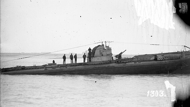 Aufgetauchtes U-Boot mit Besatzung auf See vor einer Küste