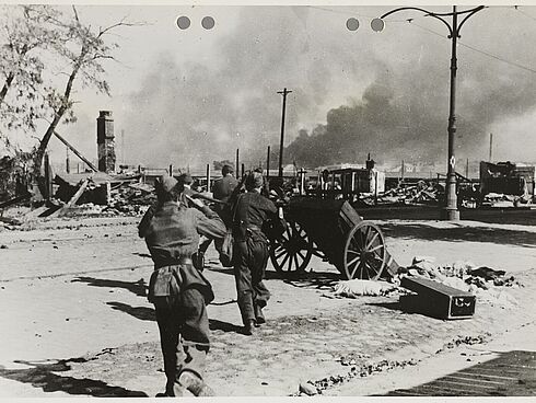Von hinten fotografierte Soldaten stürmen über eine Straße.