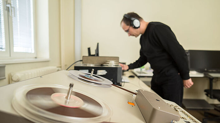 Ein Mitarbeiter des BStU mit Kopfhörern an einem Abspielgerät für Tonträger