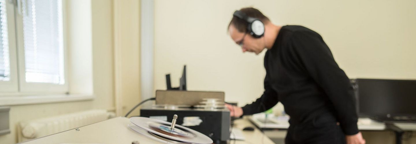 Ein Mitarbeiter des BStU mit Kopfhörern an einem Abspielgerät für Tonträger