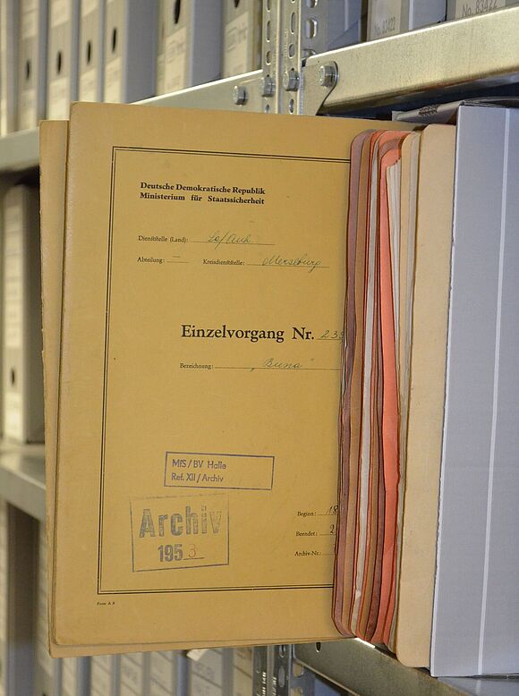Akte aus dem Stasi-Unterlagen-Archiv Halle, die halb aus einem Aktenregal gezogen wurde.