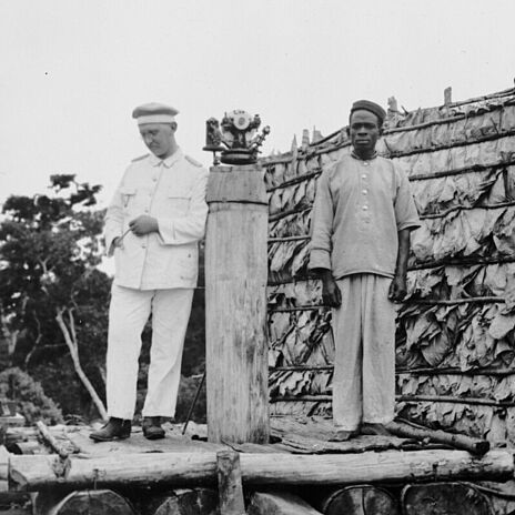 Ein weißer und ein schwarzer Mann bei der Grenzvermessung der Süd- und Südostgrenze von Kamerun gegen das französische Kongogebiet