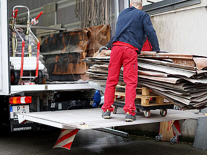 Das Bild zeigt, wie einige Kupferplatten aus einem LKW entladen werden.