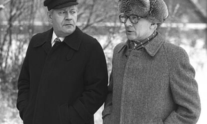 Schwarz-Weiß-Foto von Helmut Schmidt und Erich Honecker in Mänteln bei einem Winterspaziergang