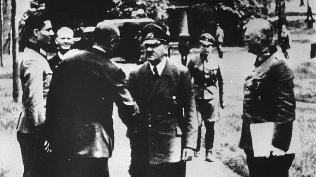 Schwarz-Weiß-Aufnahme mit Stauffenberg, Hitler und weiteren Personen beim Händeschütteln und Reden
