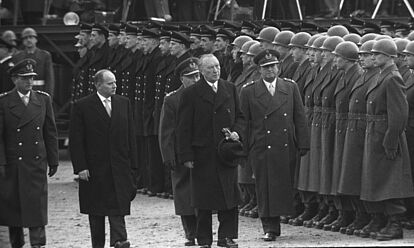 Bundeskanzler Konrad Adenauer und Verteidigungsminister Theodor Blank schreiten bei ihrem Besuch in Andernach zusammen mit drei hochrangigen Bundeswehroffiziere eine angetretene Formation von Soldaten des Heeres und der Marine ab. Im Hintergrund stehen Pressefotografen.
