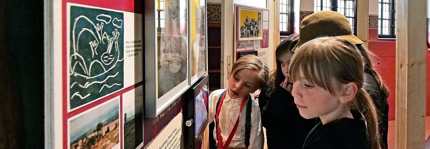 Kinder stehen vor einer Stele in der Ausstellung 'Parole: Funkenschlagen!'.