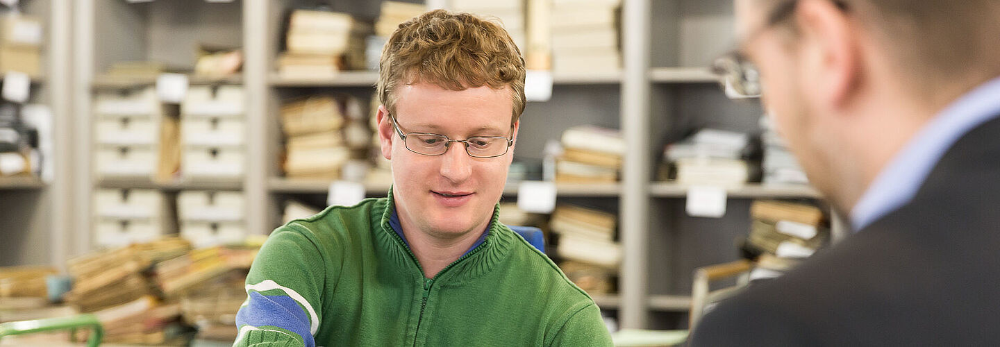 Ein Mitarbeiter bei der Erläuterung und Aushändigung eines Benutzungsantrages an einen Benutzer.