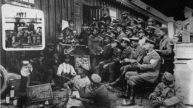 Nordfrankreich: Provisorisches Kino vor einer Holzbaracke. Soldaten vor der Leinwand sitzend, Filmvorführer am Projektor, 1915