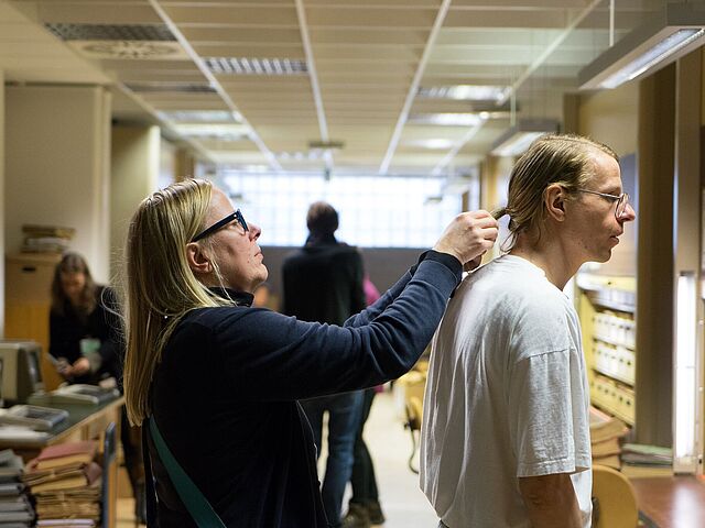 Frisur wird gerichtet Eine Frau richtet den Zopf des Gundermann-Darstellers Alexander Scheer.