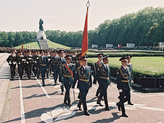 Parade russischer Soldaten vor dem sowjetischen Ehrenmal in Berlin-Treptow im August 1994 anlässlich der Verabschiedung der GUS-Streitkräfte aus dem wiedervereinigten Deutschland. An der Spitze der Parade marschiert eine Gruppe von Offizieren und Fahnenträgern.