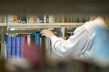 Bücherregal, vor dem eine Frau steht