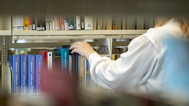 Bücherregal, vor dem eine Frau steht