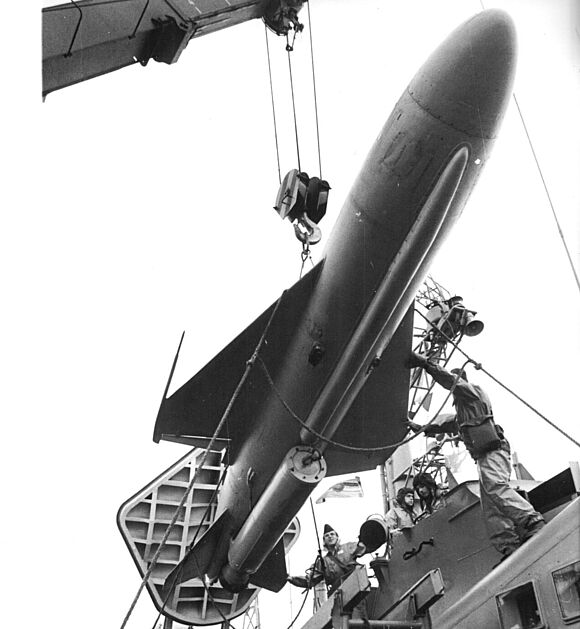 Eine Anti-Schiffs-Rakete vom Typ P-15 (NATO-Bezeichnung SS-N 2 „Stxy“) hängt an einem Kran und wird in eine Abschussanlage auf dem Raketenschnellboot „Otto Tost“ hinuntergelassen.
