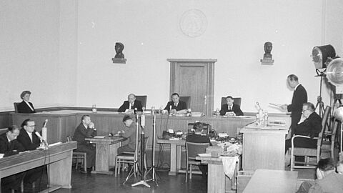 Gerichtssaal, in dem erhöht die Richter und seitlich die Angeklagten sitzen.