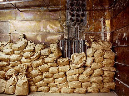 Das Bild zeigt eine Stapel mit Papiersäcken in einem mit Kupferplatten verkleideten Raum.