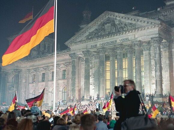 Bild vom Hissen der Bundesfahne vor dem Reichstag in der Nacht vom 2. zum 3. Oktober 1990 in Berlin
