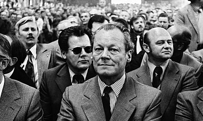 Schwarz-Weiß-Aufnahme von einem großen Saal, voll besetzt mit Personen in offizieller Kleidung, im Vordergrund Willy Brandt mit verschränkten Armen