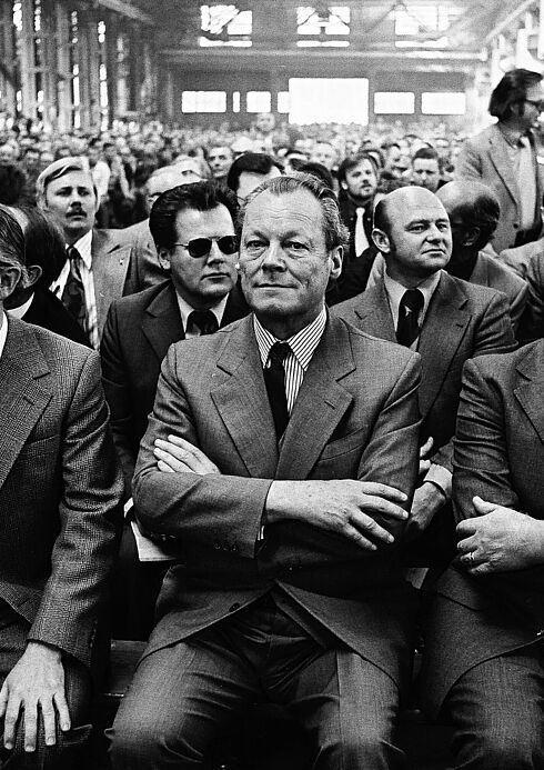 Schwarz-Weiß-Aufnahme von einem großen Saal, voll besetzt mit Personen in offizieller Kleidung, im Vordergrund Willy Brandt mit verschränkten Armen