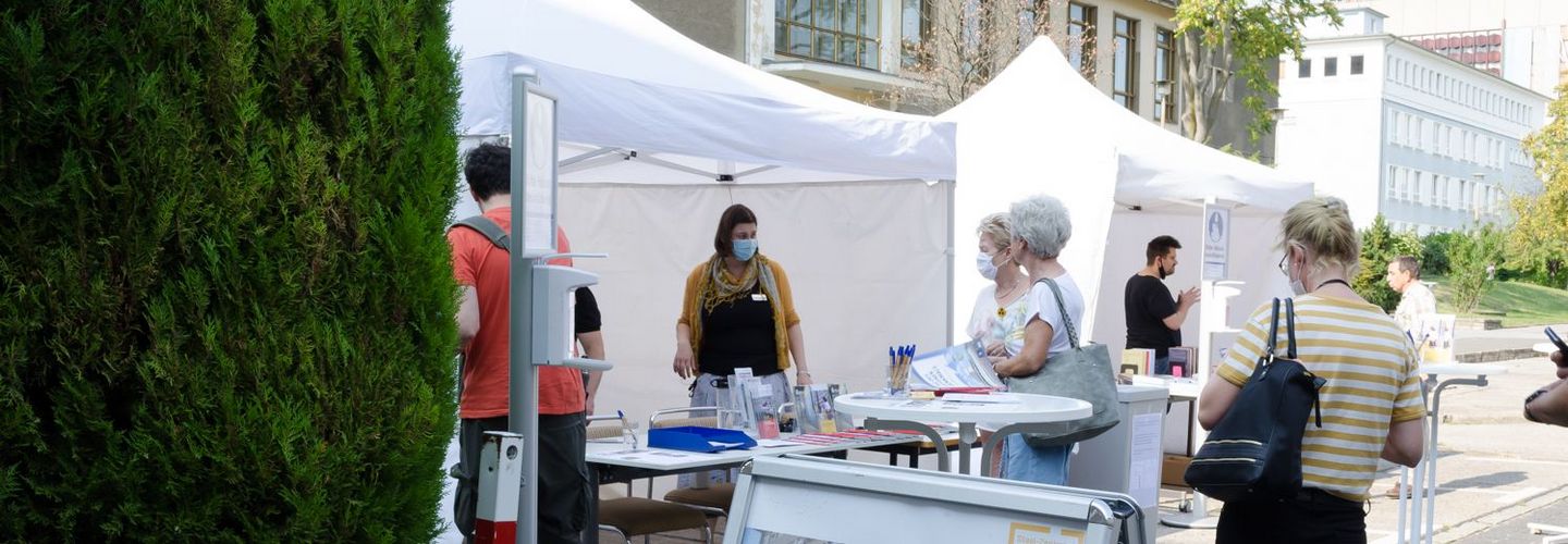 Besucherinnen und Besucher stehen vor den Informationsständen auf dem Gelände 'Stasi-Zentrale. Campus für Demokratie'.