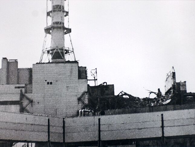 Nahaufnahme des Daches von Reaktorblock 4 mit den Trümmern nach der Explosion. Im Hintergrund ist der Abluftturm zu sehen.