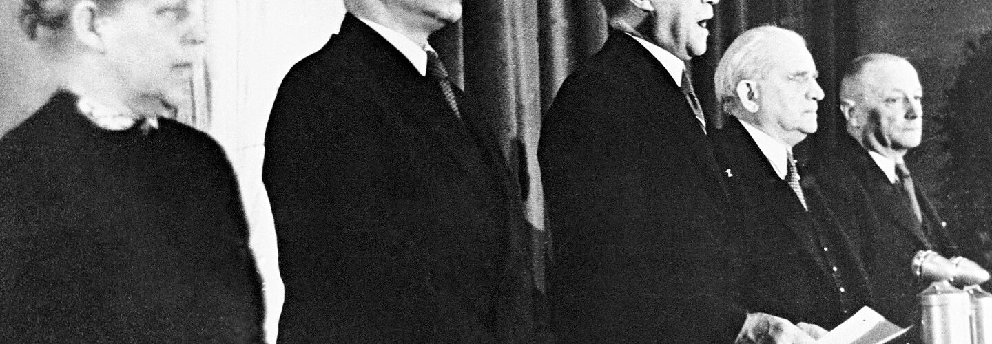 Konrad Adenauer, Präsident des Parlamentarischen Rates (M.), verkündet das Grundgesetz (GG) für die Bundesrepublik Deutschland in der Pädagogischen Akademie Bonn (v.l. Helene Weber; Hermann Schäfer; Adolf Schönfelder; Jean Stock).