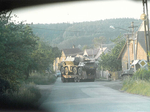 Beobachtung des Transports einer Radhaubitze vom Typ DANA in Stary Plzenec, 5. Juni 1988 Durch die Frontscheibe eines Autos fotografierter Schwertransporter mit einer Radhaubitze auf der Ladefläche