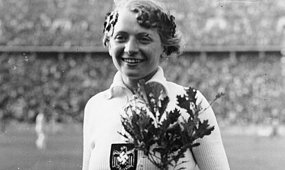 Die Speerwerferin Tilly Fleischer mit Siegerkranz und Olympia-Eiche