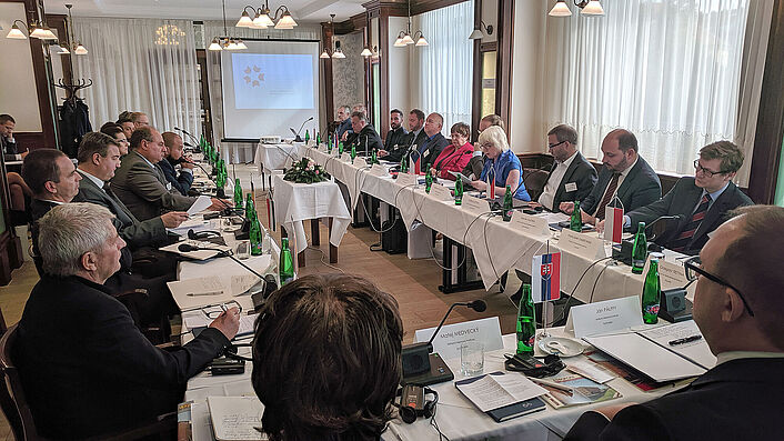 Das Bild zeigt für einen  Konferenz im Rechteck zusammengestellte Tische mit weißen Tischdecken. Die Plätze sind besetzt mit den Vertretern der osteuropäischen Geheimpolizeiarchive.