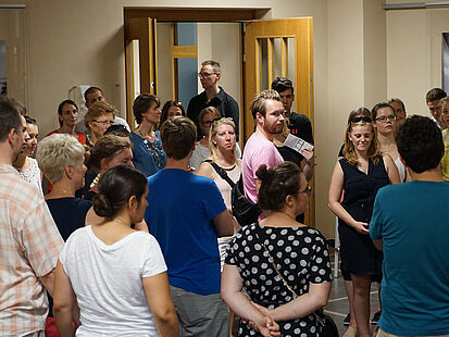 Besucher stehen im Foyer der Ausstellung "Einblick ins Geheime". Eine Mitarbeiterin hält eine Führung ab.