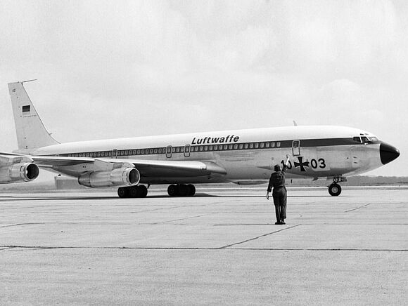 Eine Boeing 707 der Flugbereitschaft steht auf einem Flugfeld. Die Maschine trägt die Kennung 10+03. Vor der Maschine steht ein Soldat des Bodenpersonals.