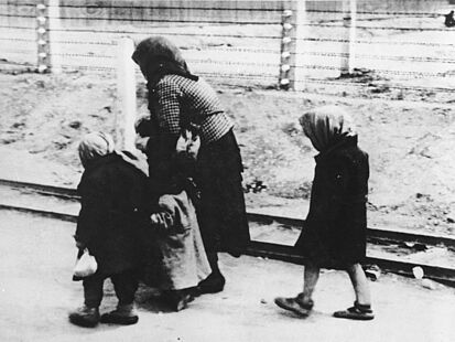 Zu sehen sind eine gebückt gehende Frau und drei kleine Kinder.