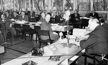 Foto des Bundestagsausschusses für Fragen der europäischen Sicherheit. Männer in Anzügen sitzen an Tischen, vor ihnen liegen Unterlagen. Ein Mitglied blickt direkt in die Kamera. Das Foto wurde hinter dem Tisch des Vorsitzenden aufgenommen.